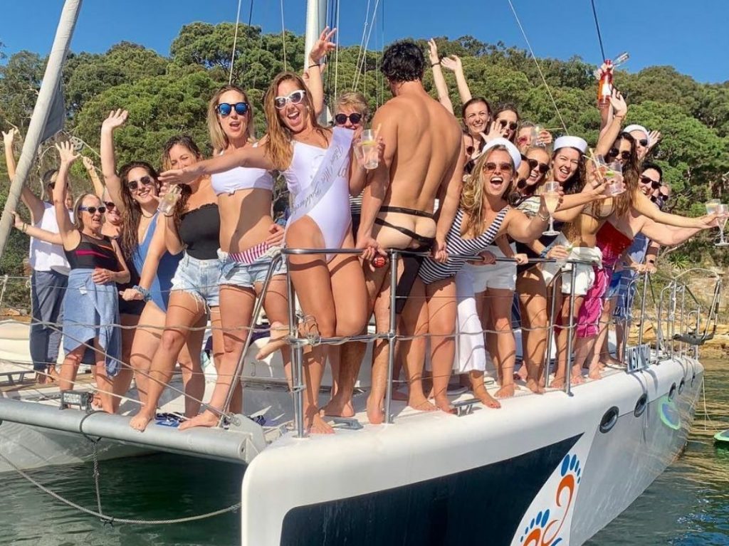 Girls with a topless waiter on their Sydney Hens Party Boat Cruise